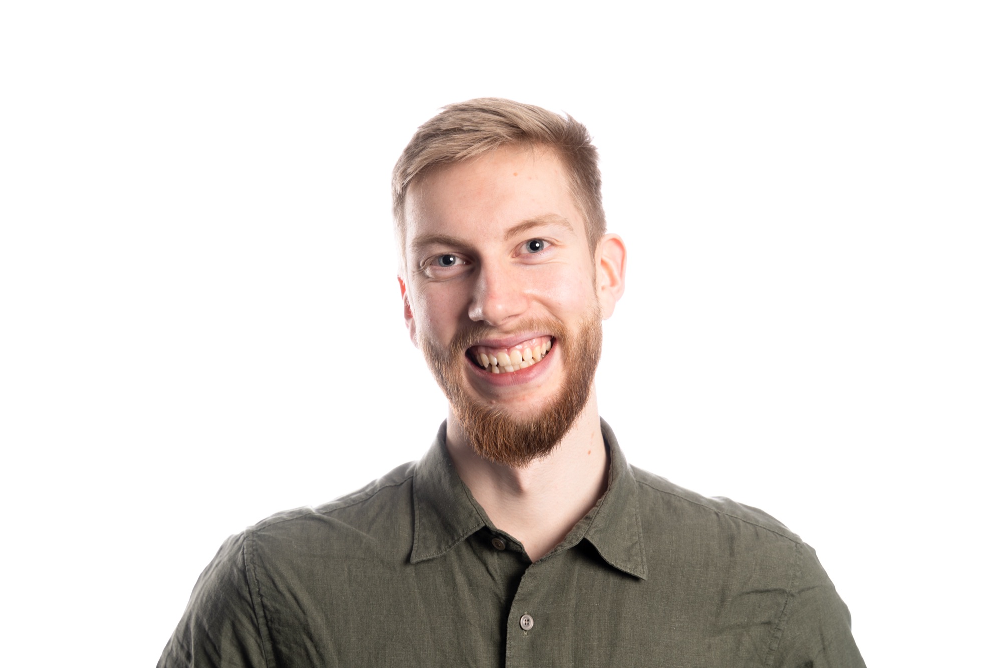 Studio portrait of a smiling bearded man in an olive shirt on a white background
